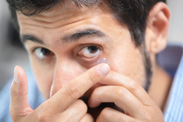 man inserting contacts lens